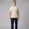 Model wearing a cream-colored t-shirt with a broad white stripe across the chest and dark blue jeans