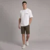 Man wearing a white t-shirt with YOLO REPUBLIC printed on the chest, olive green shorts, and white sneakers