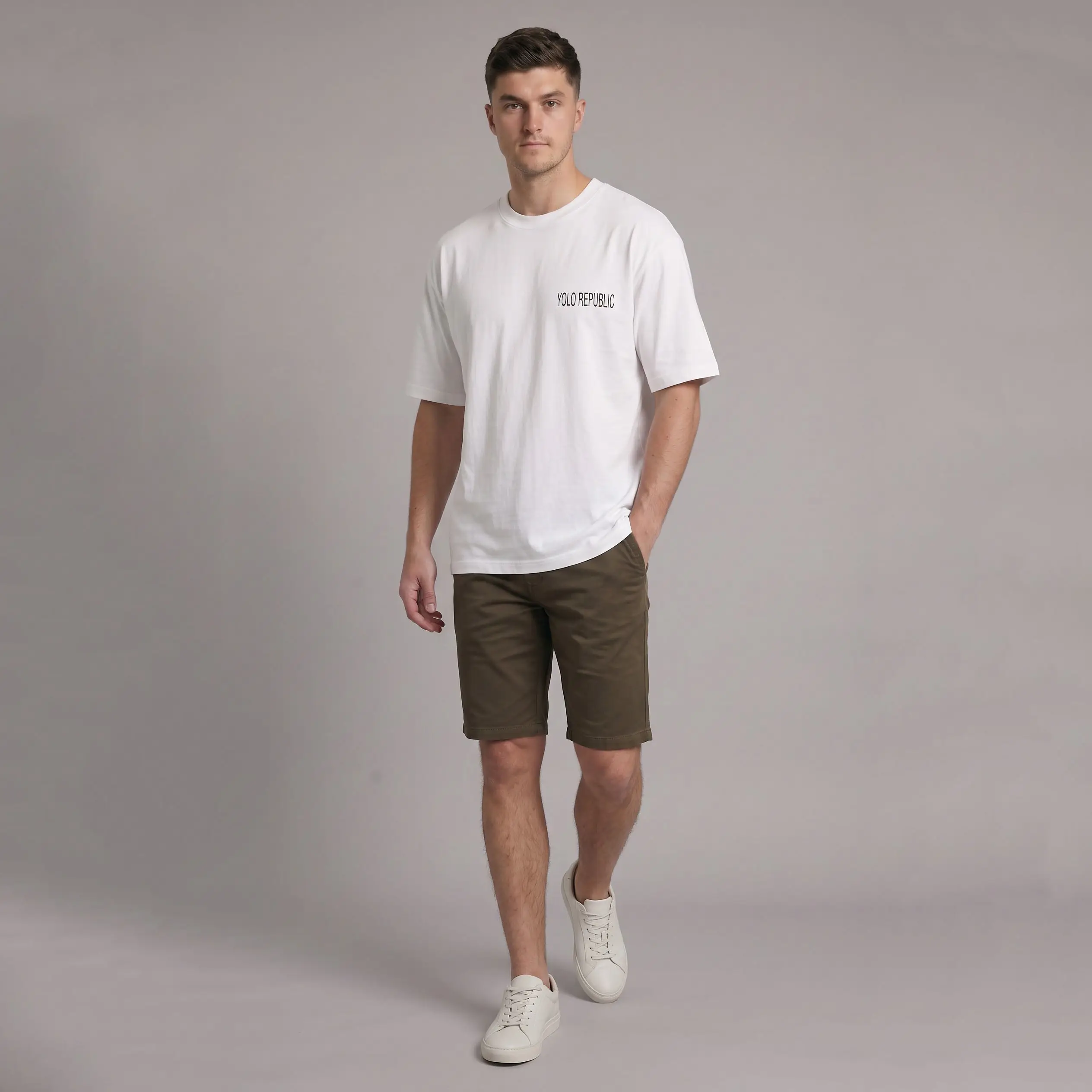 Man wearing a white t-shirt with YOLO REPUBLIC printed on the chest, olive green shorts, and white sneakers